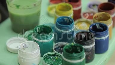 一套多种颜色的泥在塑料罐子上。 旋转多色背景。 很多水纹漆水罐